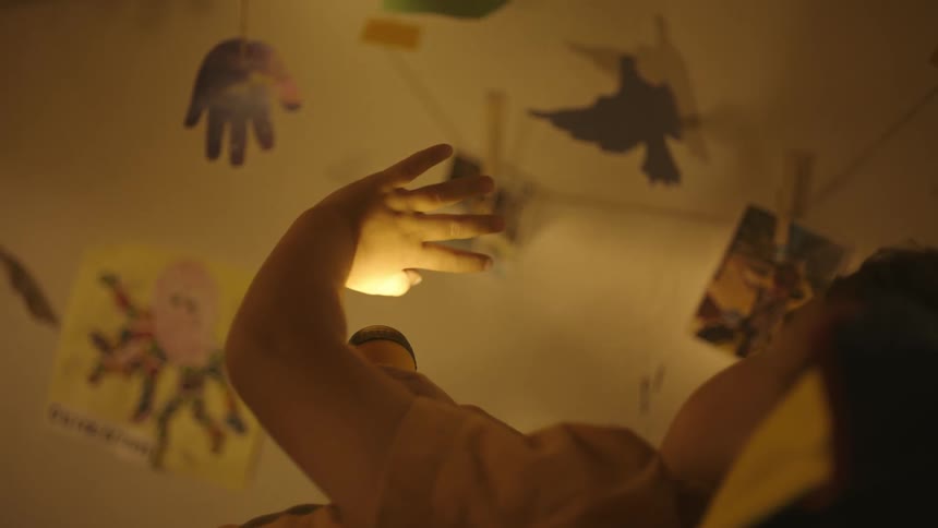 Boy lying down with his hand raised up playing