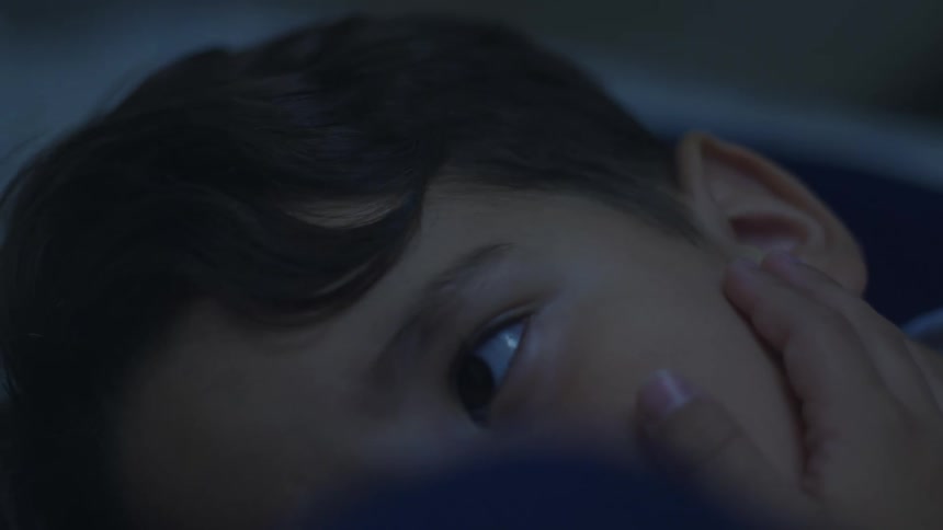 A young boy touches another boys face while they are lying down