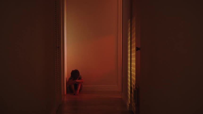 A clip of a boy sitting in the corridor scared