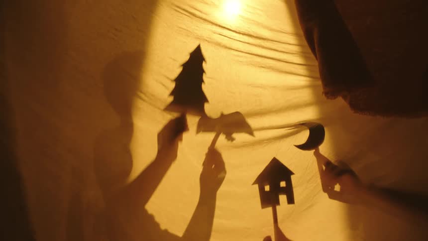 Shadow of two children playing with objects on a sheet