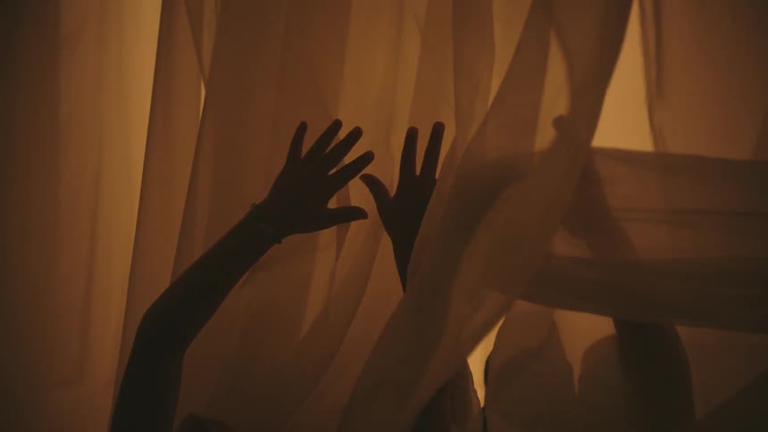 Two people waving their hands around inside of see through fabric