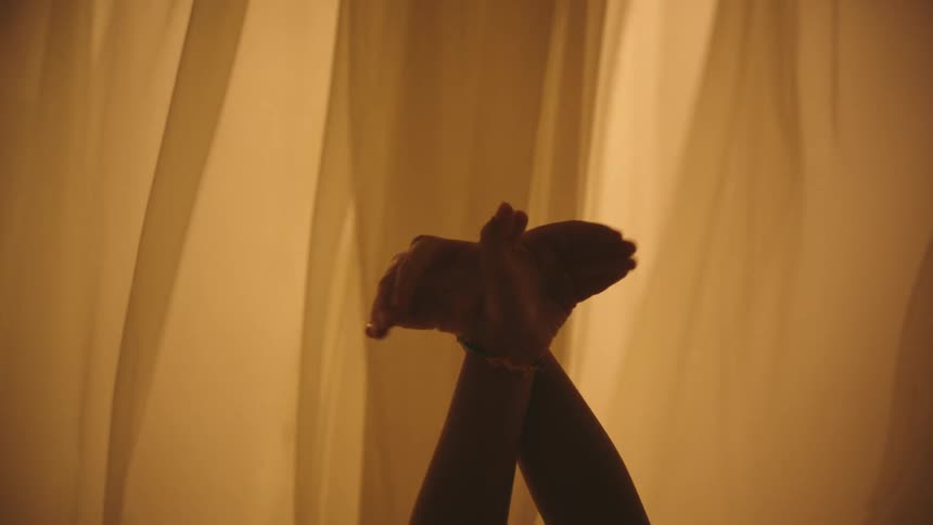 Two boys play around by flapping their hands as thin fabric blows around them