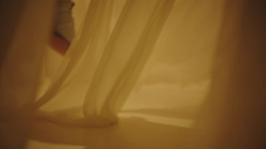 A young boy runs around inside an area filled with billowing fabric