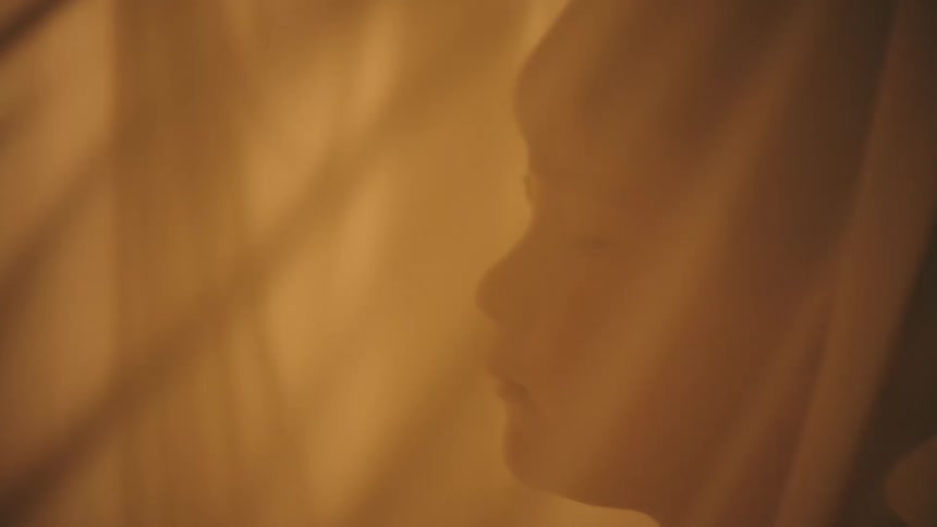 A boy with his eyes closed behind a semitransparent sheet