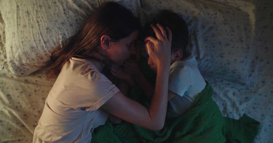 Mother lying in bed taking care of her sleeping son