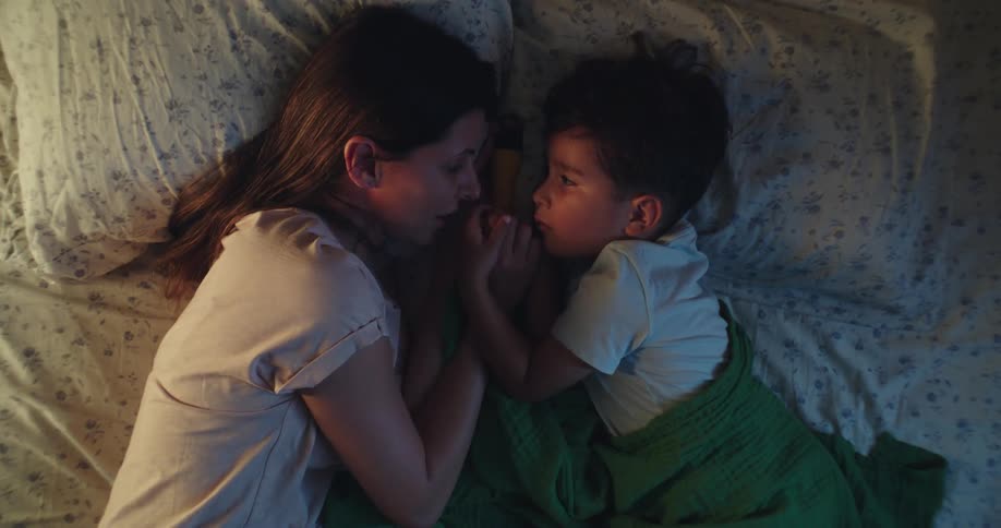 A mother and son lay in bed together