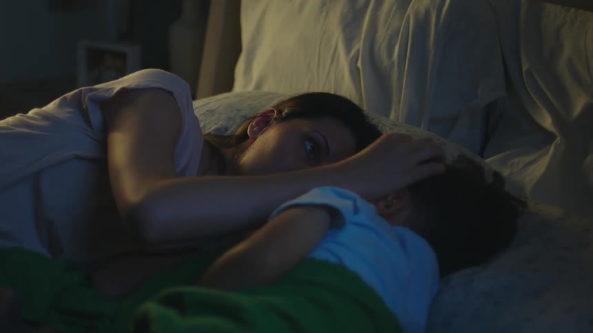 Mother lying in bed with her sleeping son