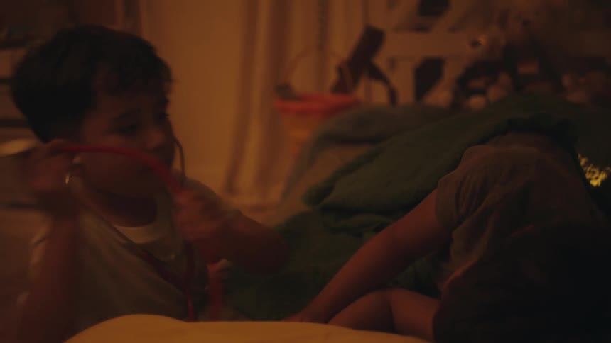 Two boys playing in their bedroom at night with one of them using nursing equipment