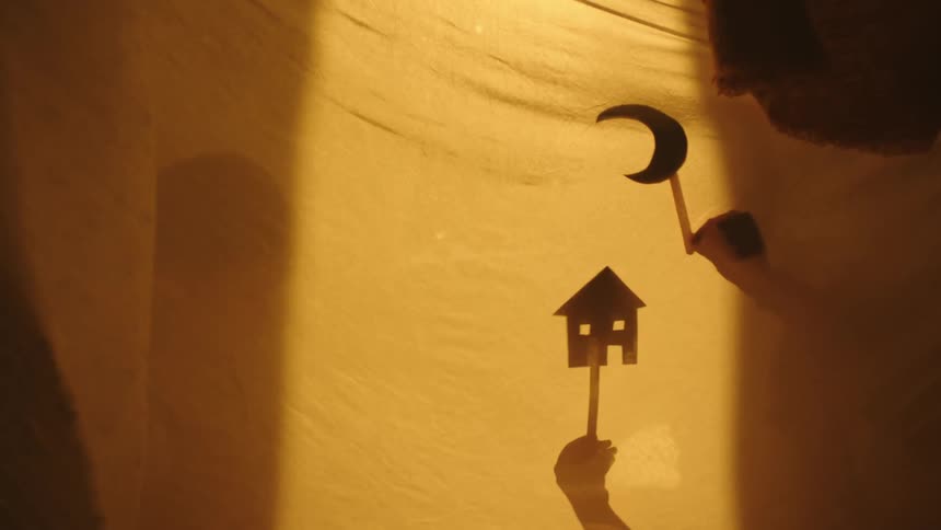 Hand holding a toy and casting shadow against a spread sheet