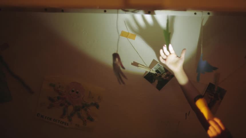 Two boys play in bed with a flashlight and a hanging decoration