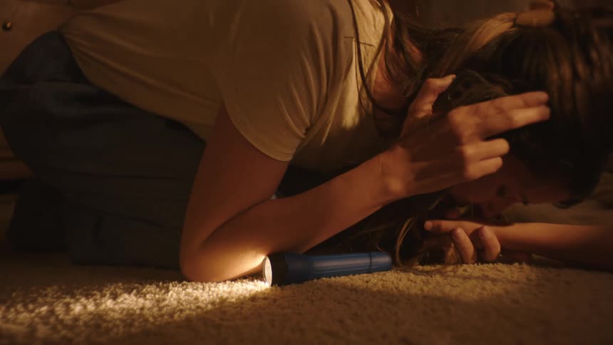 Mother on the phone kissing a childs hand on the floor