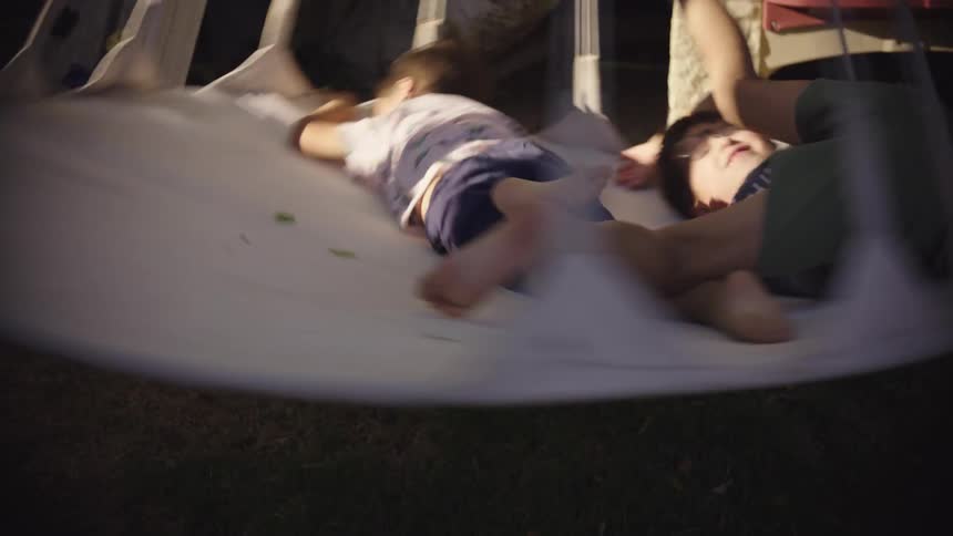 Two young boys are spinning in a rope swing on a summer day