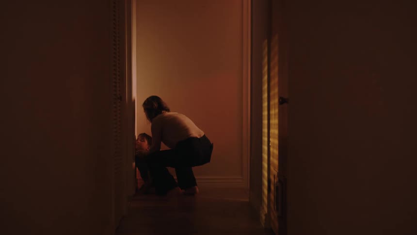 Desperate mother running down the hallway towards her son who is in the corner of a wall with red lights flashing around him