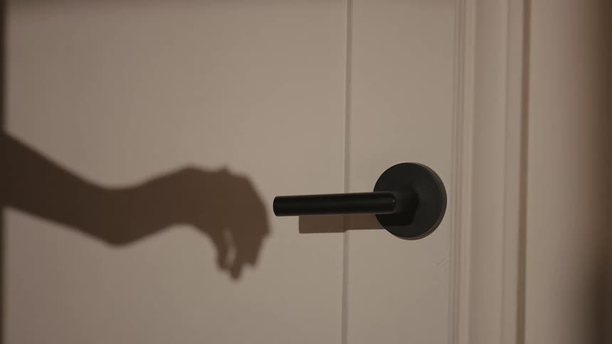 Shadow of a hand reaching for a door handle