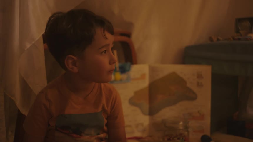Little boy sitting in a room with toys around