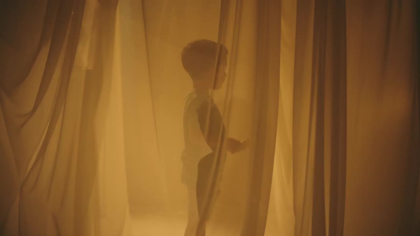 Child between curtains holding a flashlight