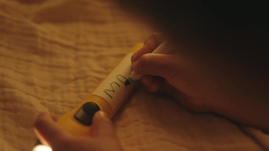 A child writing his name on a lantern with a green marker