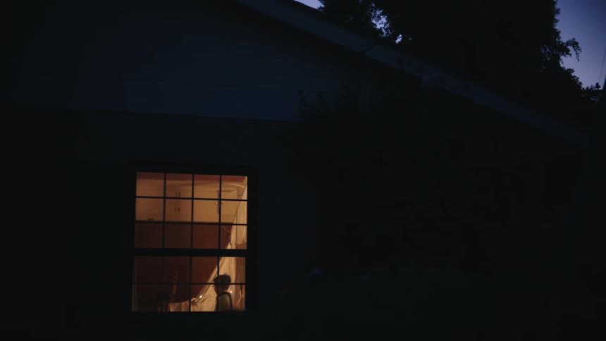 Outside view of a house at night with a window with a light on and a hallway with children running around playing