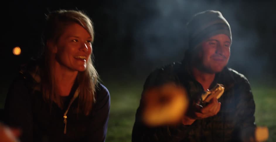 People make s'mores and chat around a campfire
