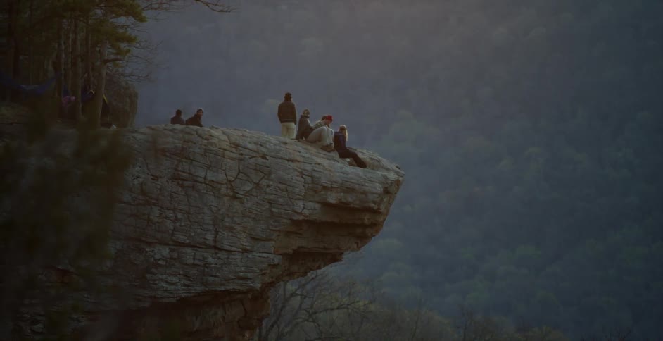 A group of people sitting on the edge of a mountain cliff
