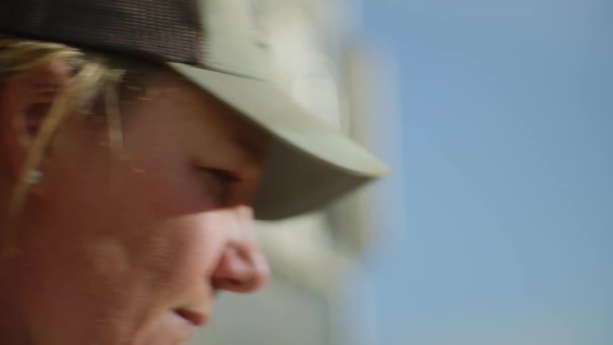 The face of a blonde woman wearing a cap who is drinking something