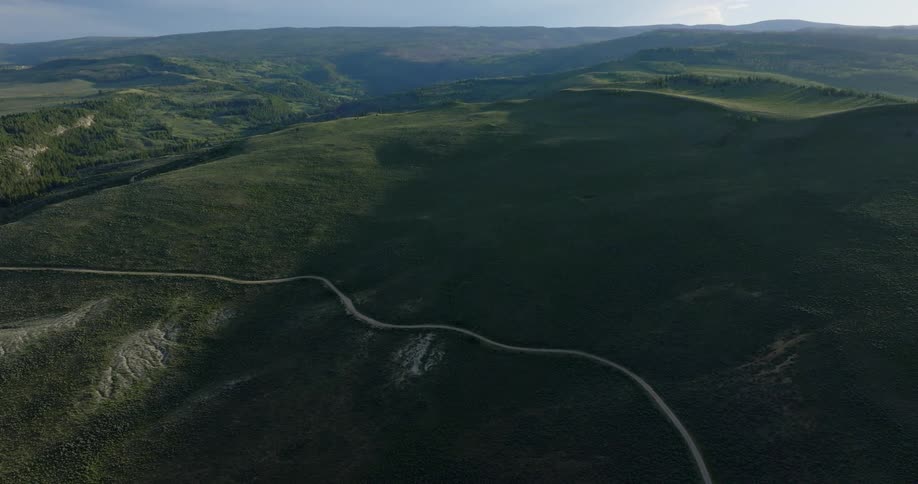 Aerial of a remote road in a green mountain range