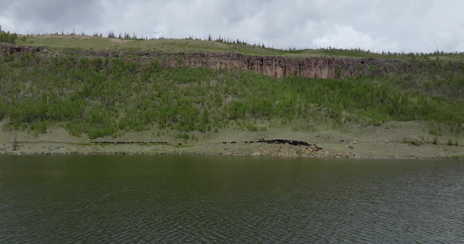 A herd of cattle near a plateau approaching a river