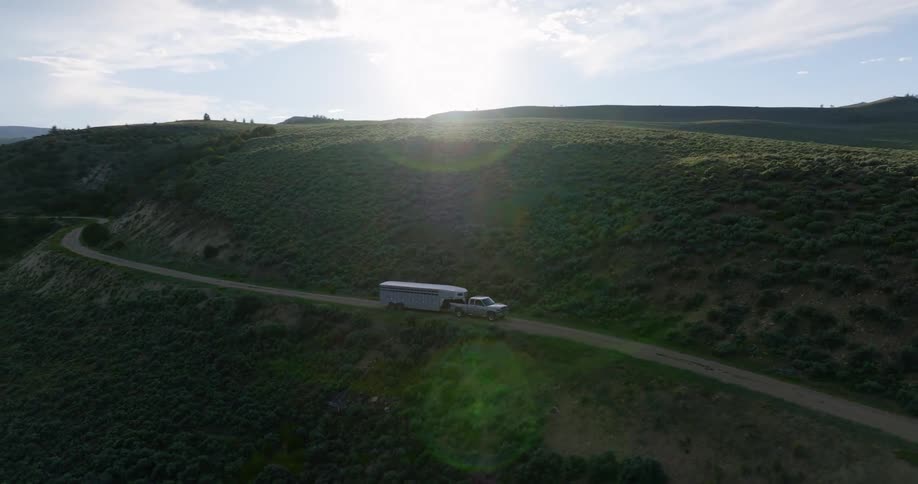 Aerial view of a pickup truck connected to a container traveling through a mountain