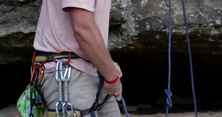 Rock climber threading his rope through his belt