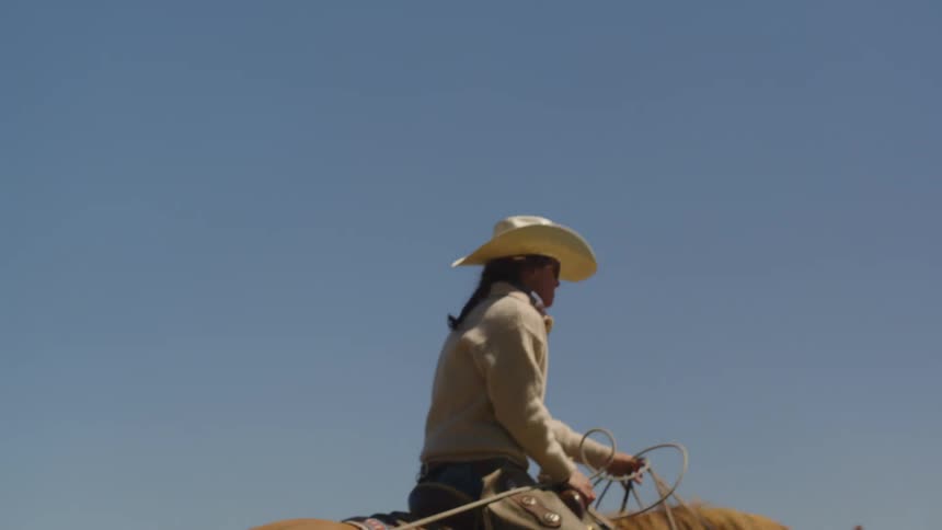 A man is riding a horse in an enclosure in the grassland field