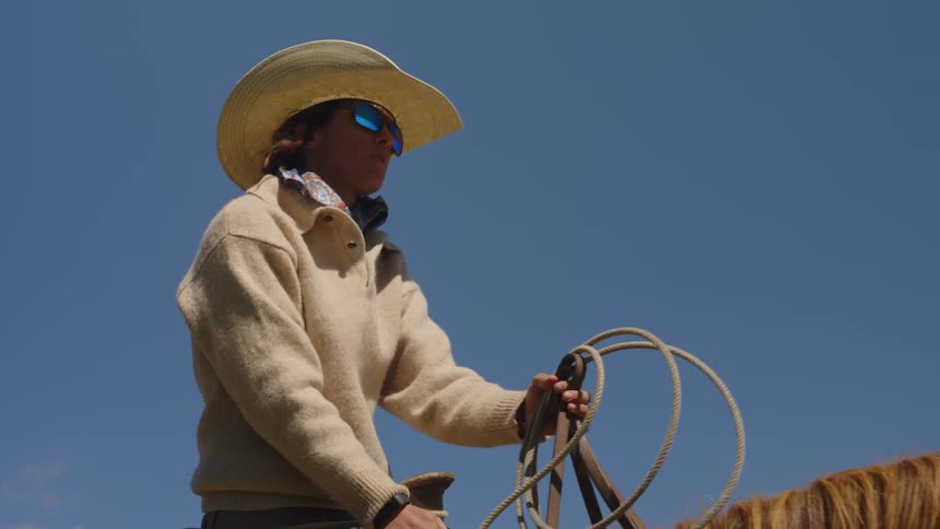 A man with a cowboy hat and sunglasses rides a horse