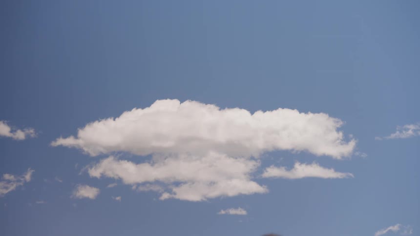 People in cowboy hats passing each other by under a blue sky with few white clouds