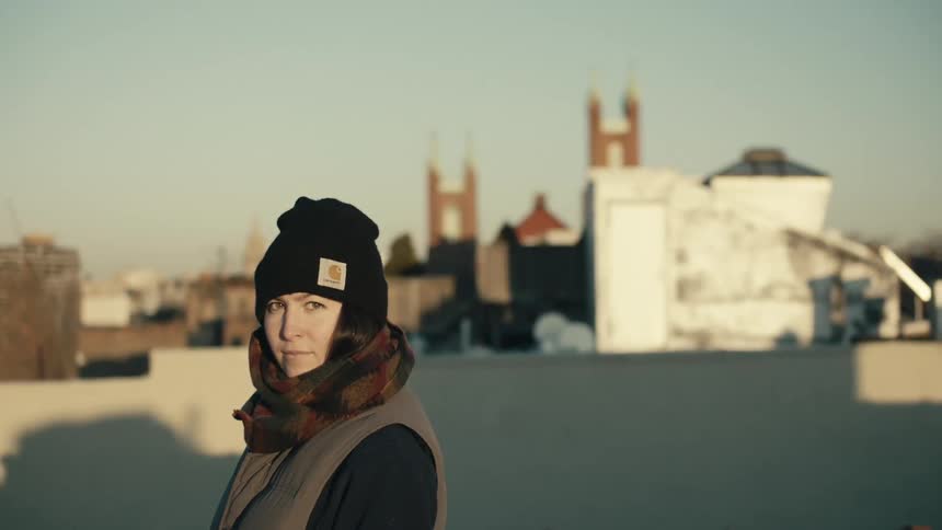 A woman stands with a city in the background