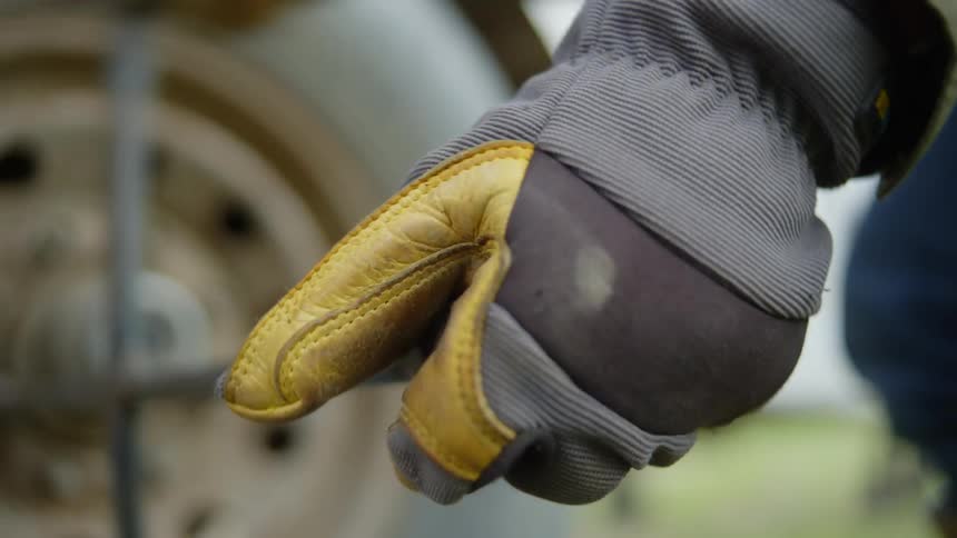 Closeup of a persons hand wearing a glove while changing a tire