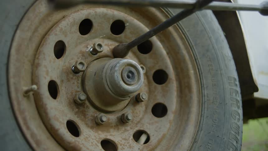 Closeup of a person changing a tire with a tire iron