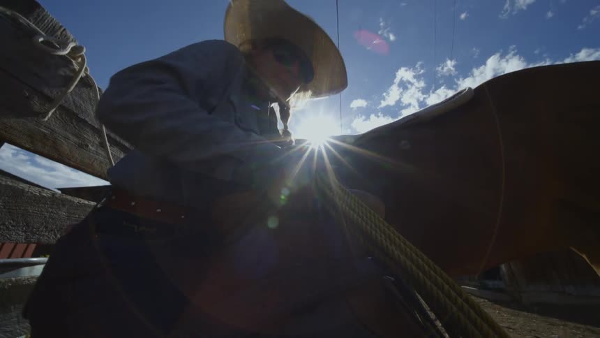 A woman grabs a saddle and readies it to go onto the horse