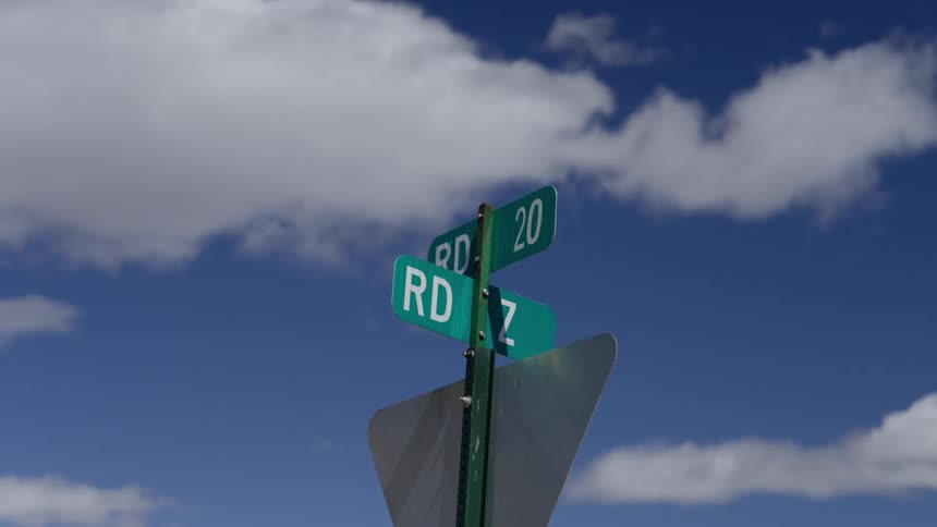 Highway signpost against a blue sky with clouds