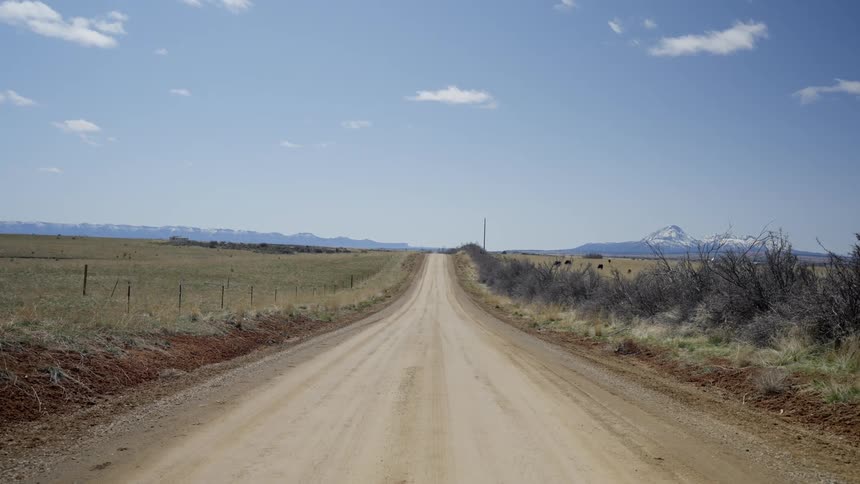 A dirt road heading straight across a grass plain