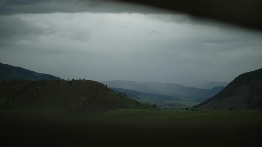 A landscape of some hills covered in green grass and a gray sky