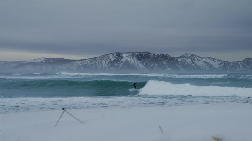 Beach landscape with a person surfing a wave