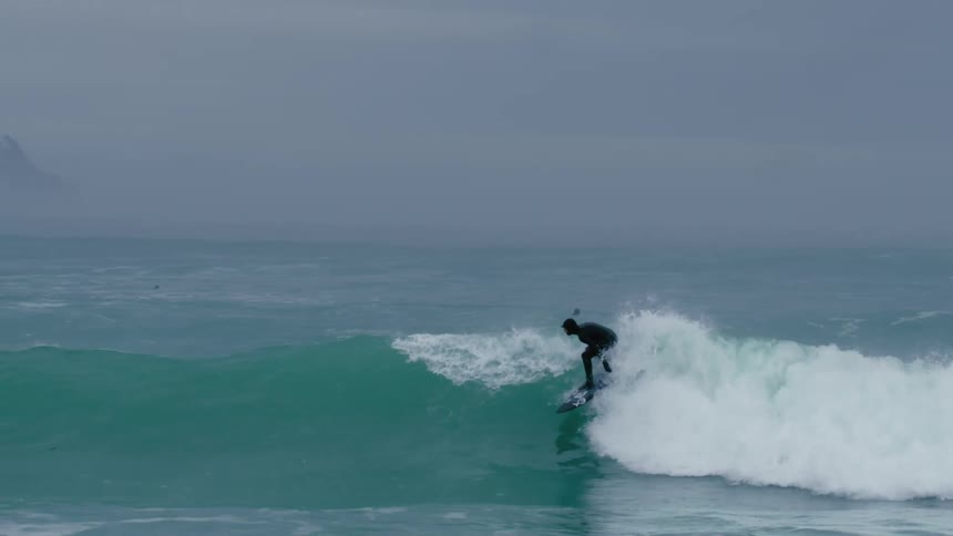 Person surfing a wave to the end with radical maneuvers