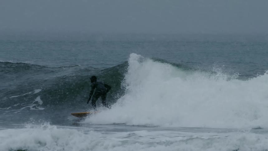 Man surfing a wave on a snowy day
