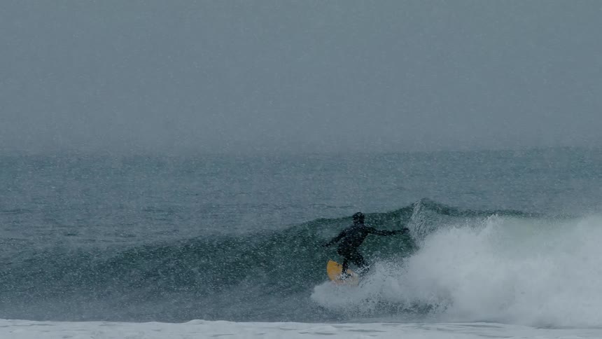 Person performing a surfboard maneuver on a wave in the ocean