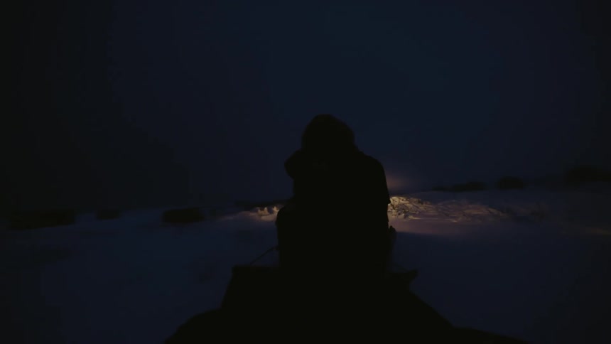 Silhouette of a person on a mobile equipment through the snow at night