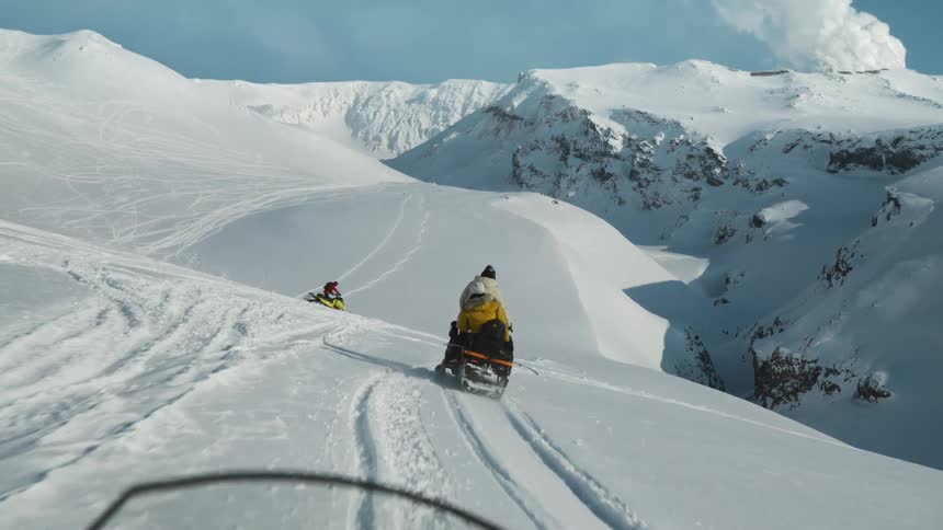 People on a snowmobile traveling through snow covered mountains