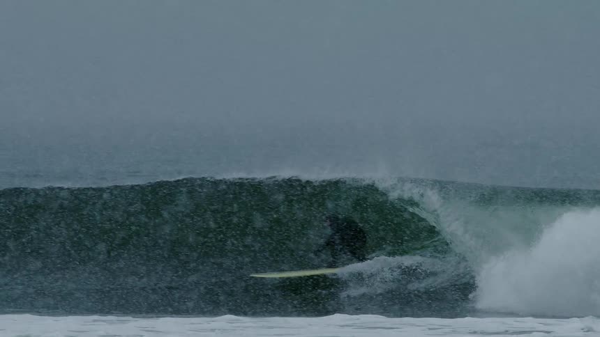 Person dropping into a wave on a snowy day