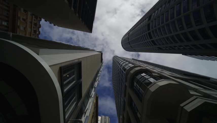 Four huge commercial buildings seen from below and contrasting with the blue sky with white clouds