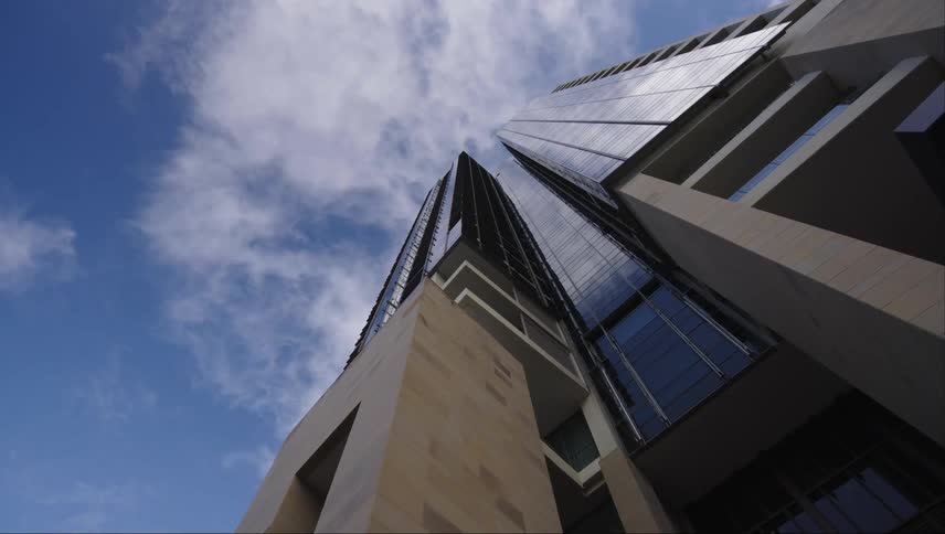 Upward view of the exterior architecture of a modern building against a blue sky with clouds