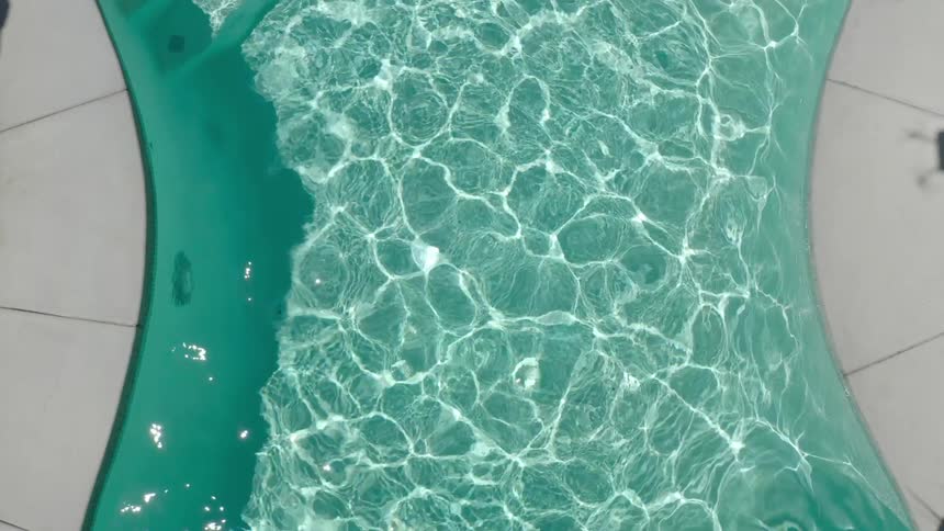 Top view of a beautiful pool with crystal clear water and the reflection of the sun