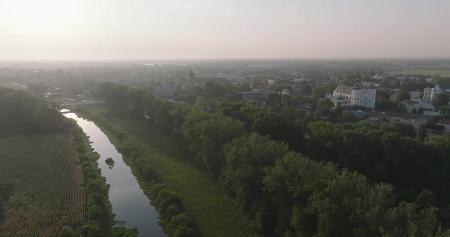 A river runs by a plain and forest near a city
